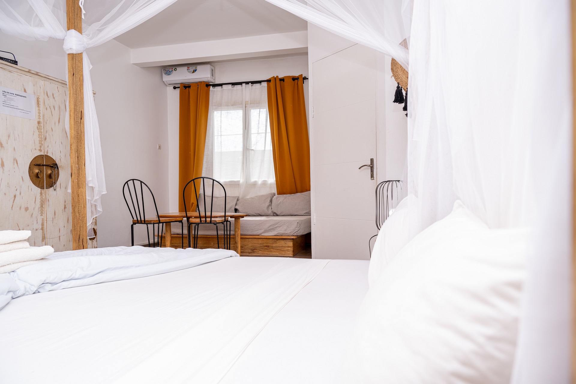 Bright room with mosquito net and seating area at Casa Mara Hotel in Dakar